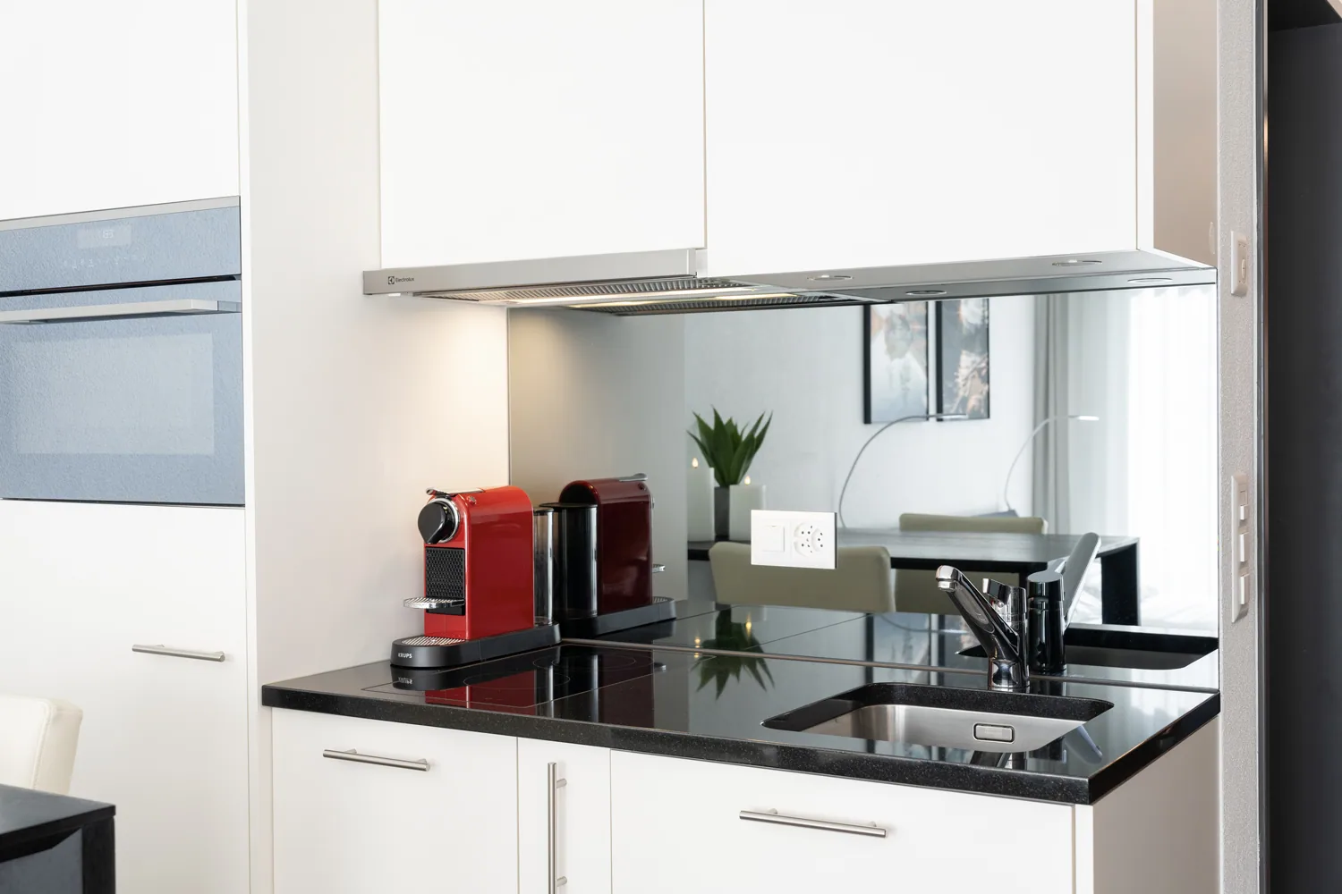 Weisse Apartmentküche mit schwarzer Arbeitsfläche und Kaffeemaschine